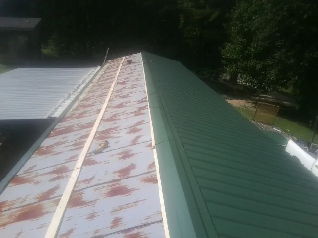Old rusted panels beside newly installed green metal roofing — Wind Damage Roof Repair by Roofing Brothers in Paynes Creek