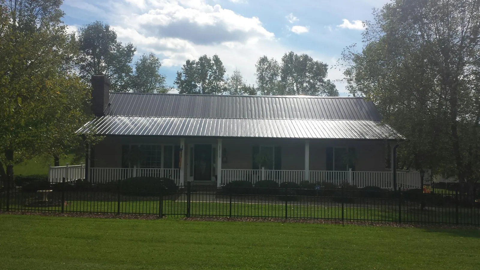 Gray metal roof on a brick ranch with a full width front porch — Gutter Guard Installation work by our crew in Paynes Creek