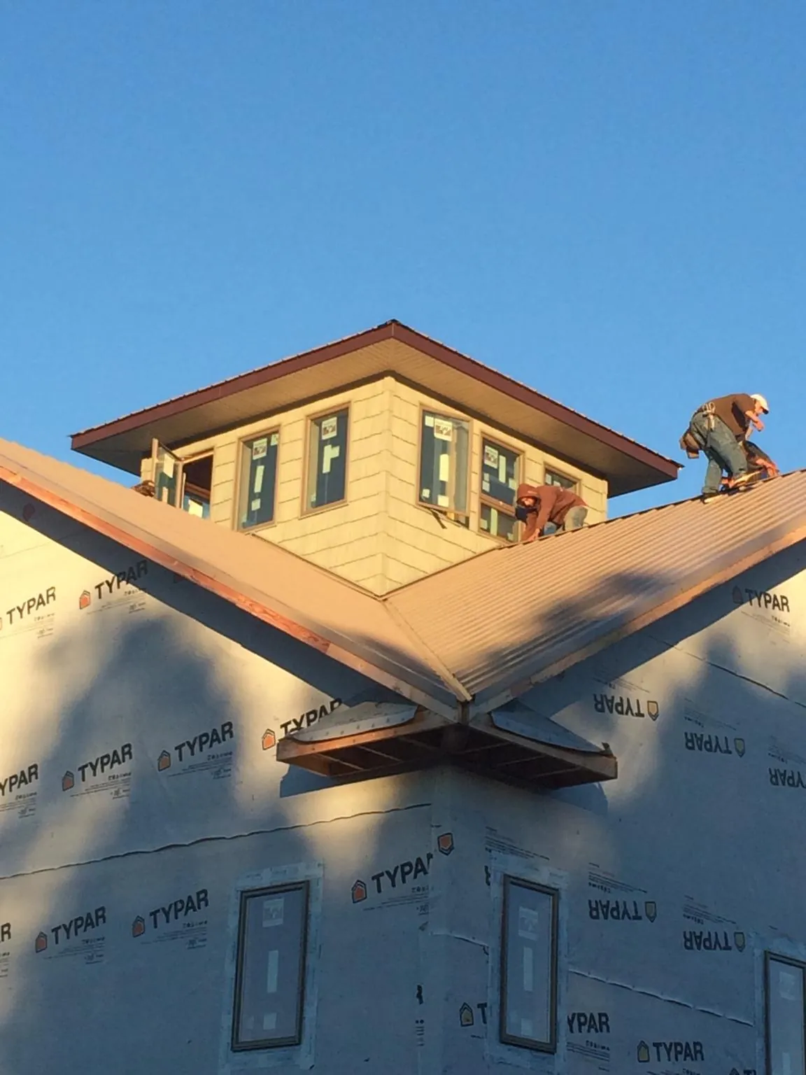 Roofers working around a rooftop cupola on a new metal roof at sunset — Roof Waterproofing in Paynes Creek by Roofing Brothers